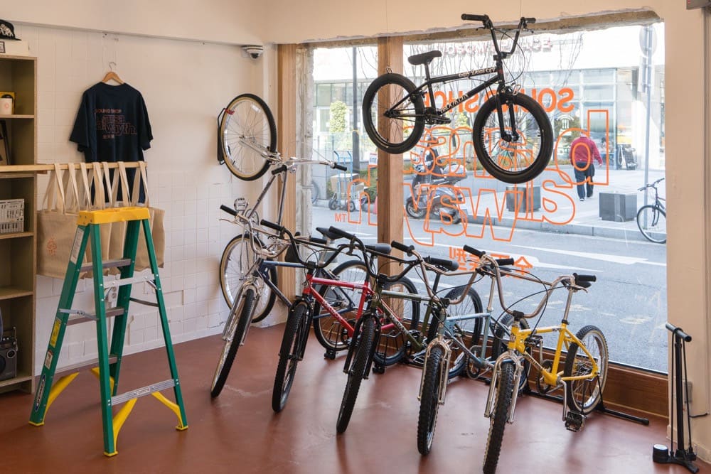 Bicycles and a ladder inside BOLT, with a passer-by visible through the window