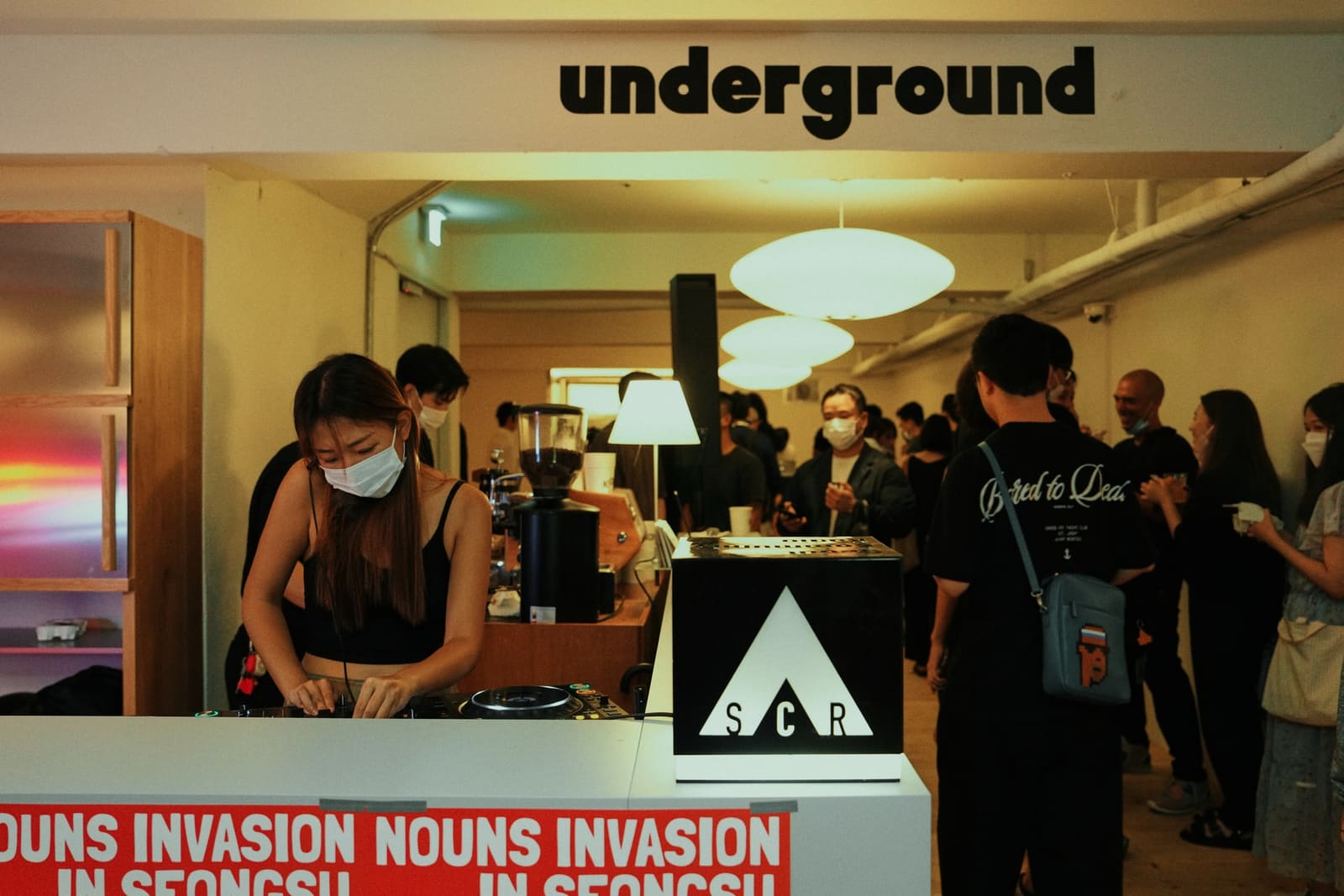 underground 사인 아래 방문객이 모인 실내와 NOUNS INVASION 배너
