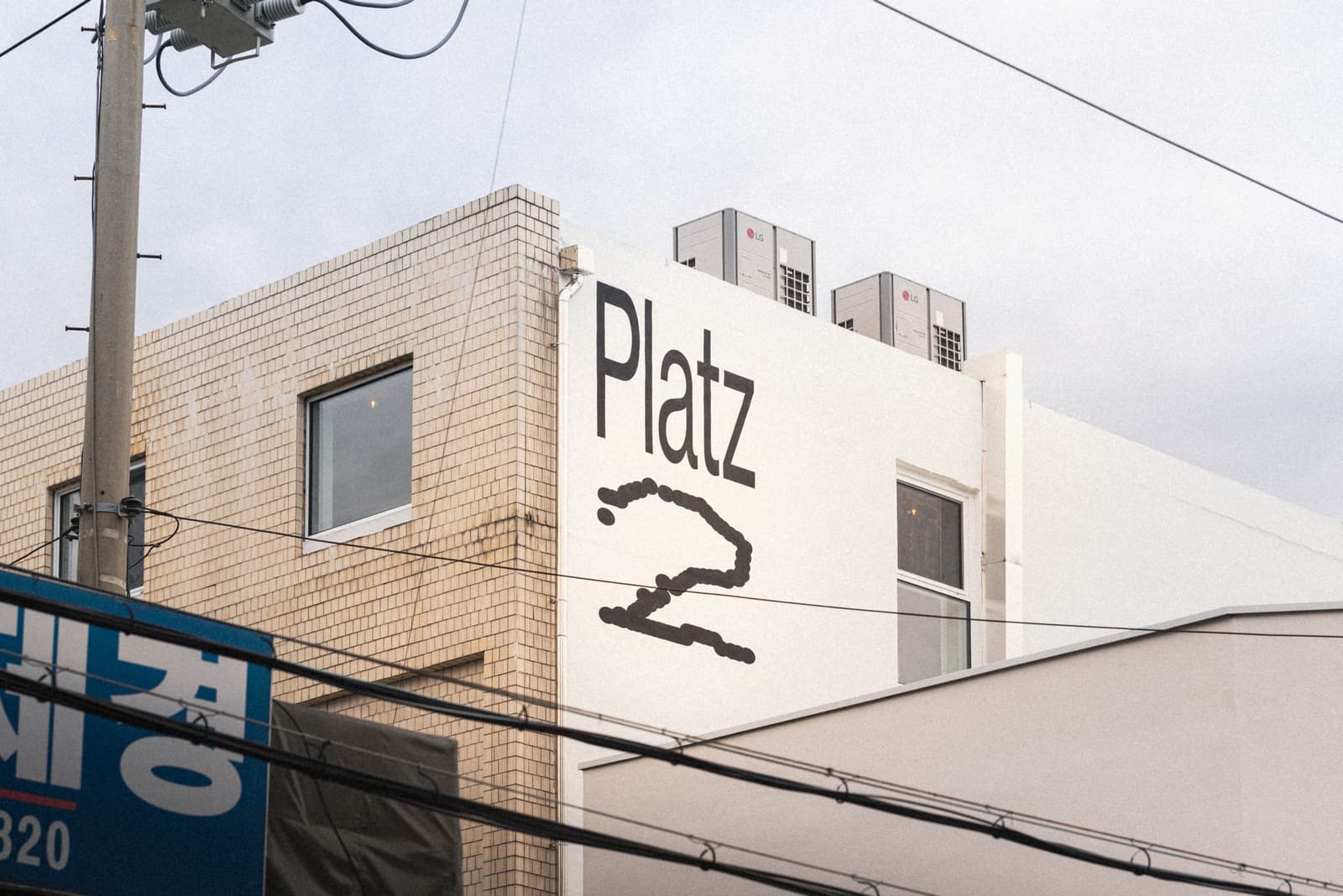 플라츠2 기록 사진: PLATZ 2 사인이 그려진 B동 흰 벽면과 타일 외벽