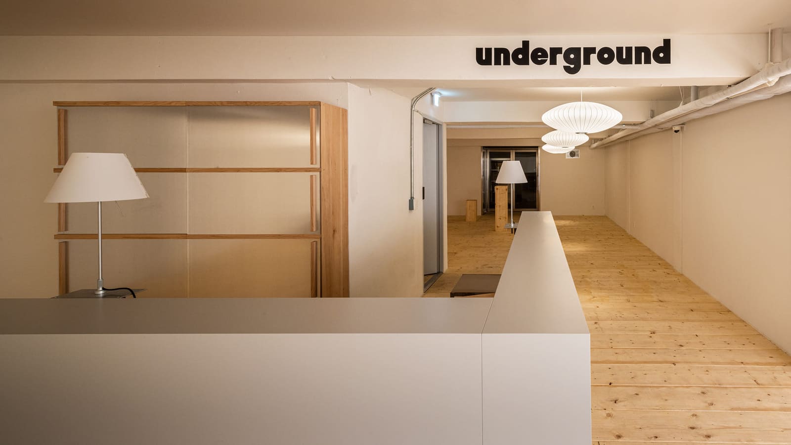 플라츠2 기록 사진: underground 사인이 있는 원목 바닥 지하 공간과 흰 카운터