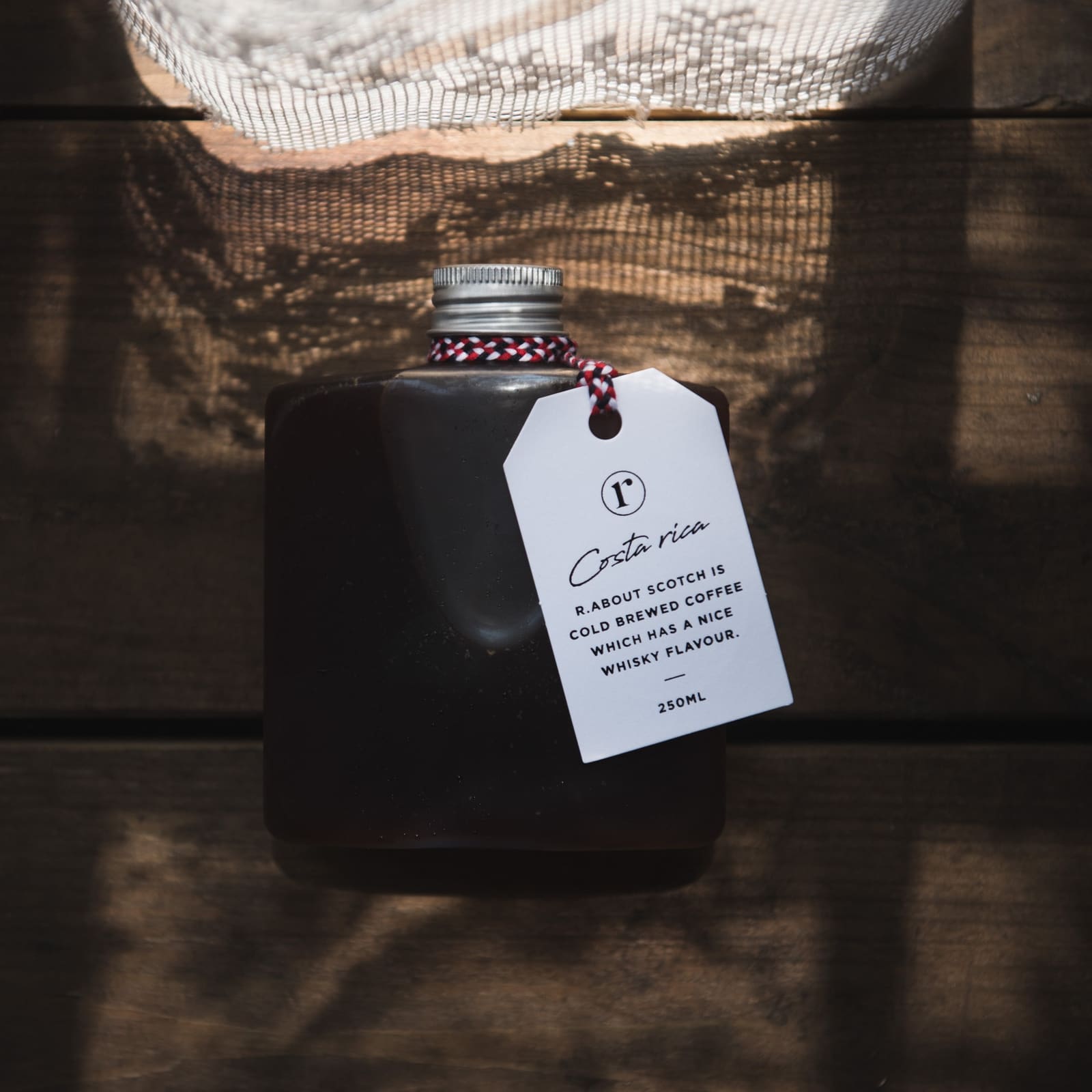 r.about archive: cold-brew bottle with a white tag against dark wood