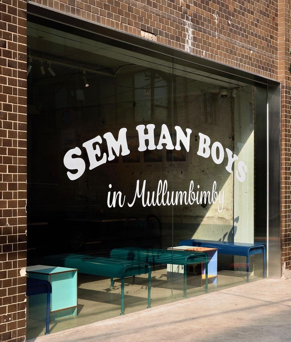 SEM HAN BOYS in Mullumbimby 글자가 쓰인 카페 포제 유리창과 내부의 청록색 벤치